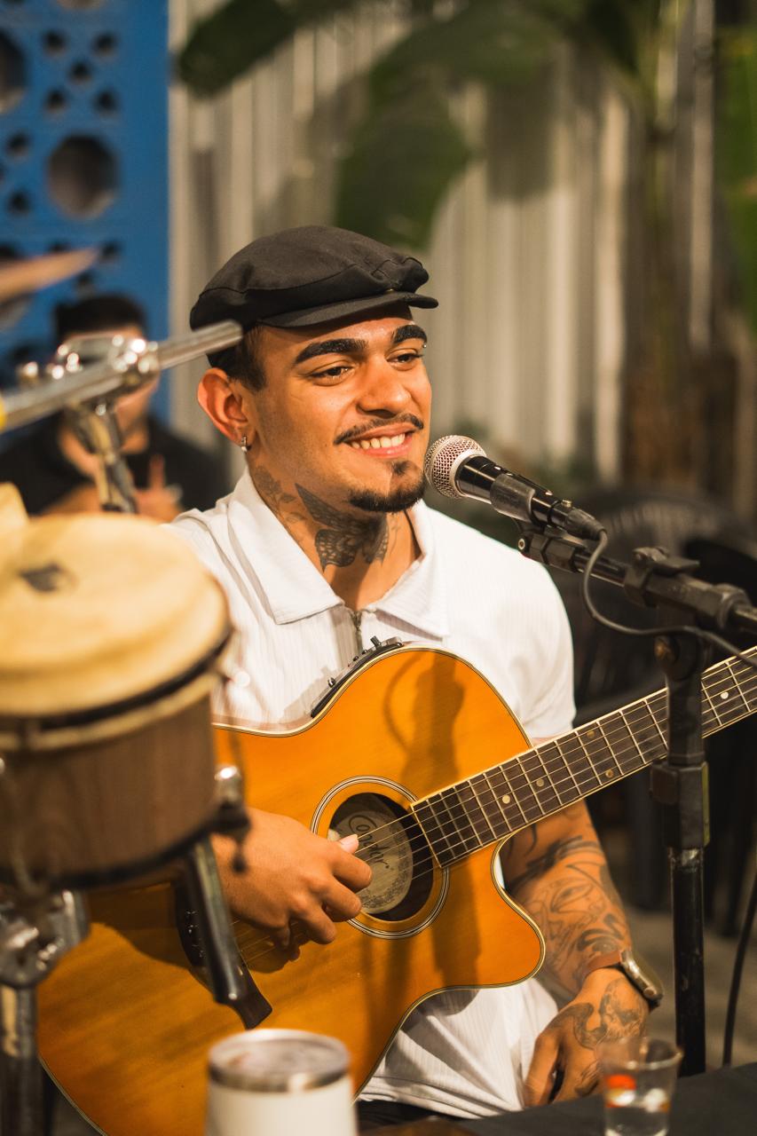 Violonista de boina preta sorrindo com o violão no colo