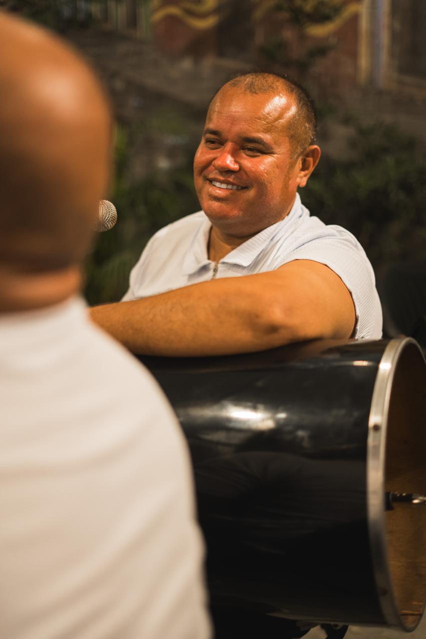 Percussionista sorrindo apoiado no tantã durante a roda